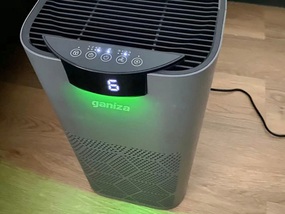 gray air purifier on hardwood floor with green nightlight on 