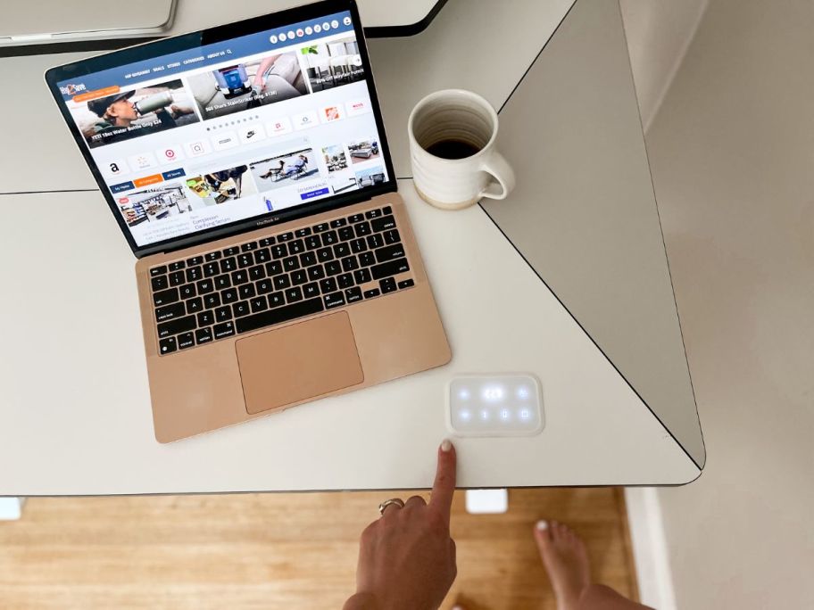 laptop on standing desk with hand pressing touchscreen buttons