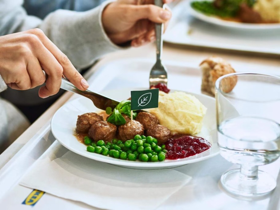 eating meatballs and mashed potatoes off a white plate at IKEA