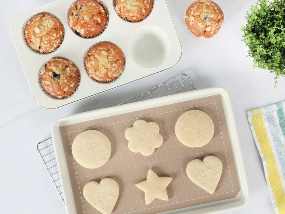 blueberry muffins in a muffin pan and cut out sugar cookies on a baking tray