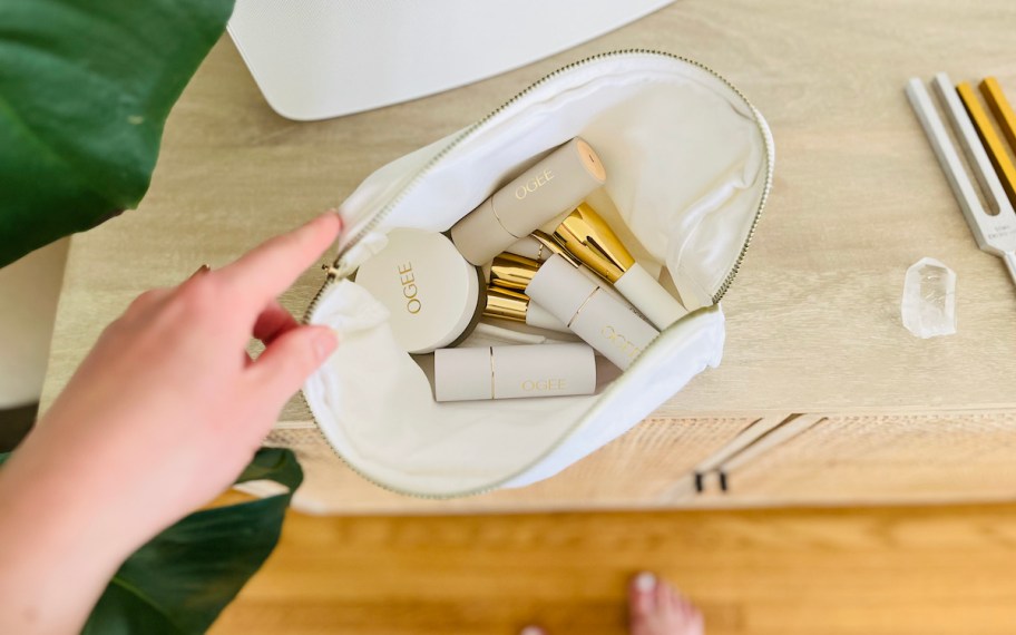 hand holding open white makeup bag