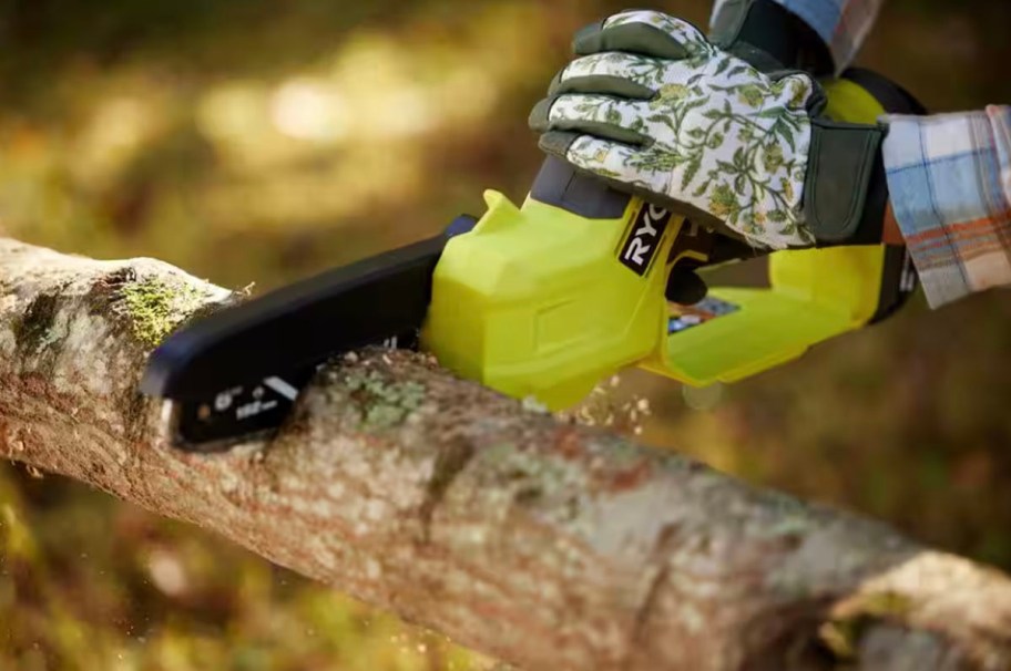 someone using green chainsaw on branch