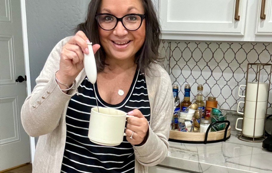 woman using a handheld coffee frother in coffee