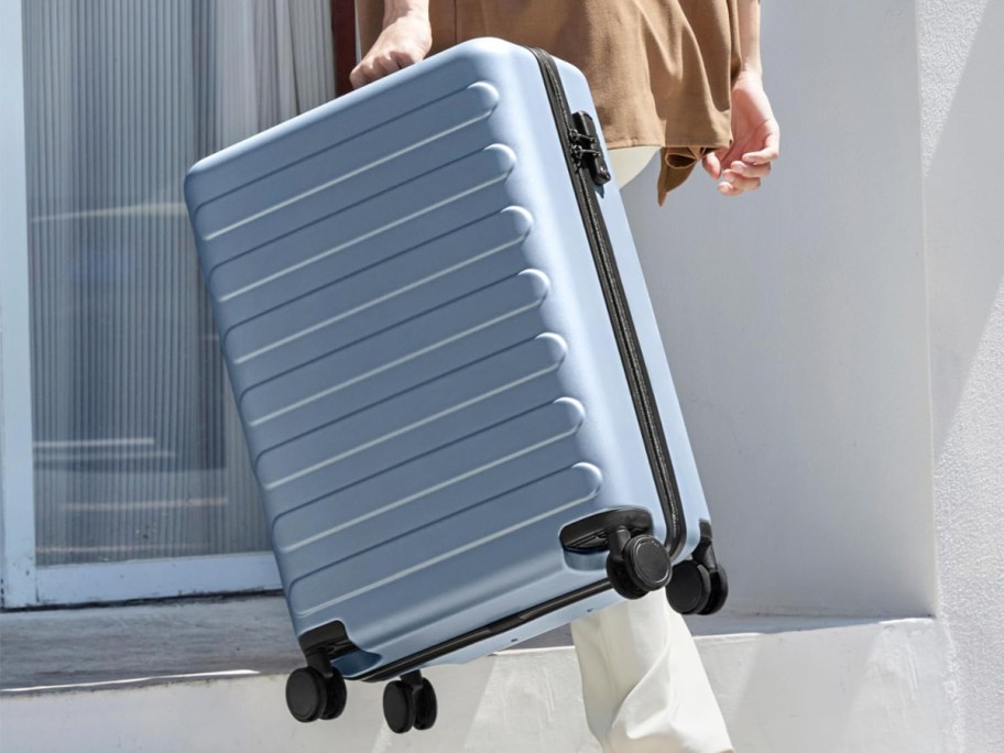 Woman holding hardside carry on luggage 