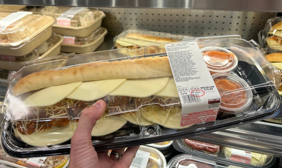 hand holding a costco prepared meal of a beef pork meatball sandwich