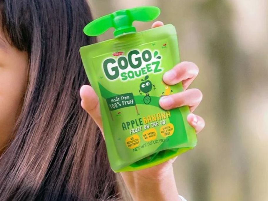 A child holding a GoGo Squeez Fruit on the Go Apple Banana pouch