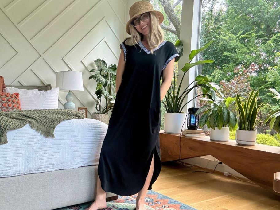 A woman wearing a long, black dress in her bedroom