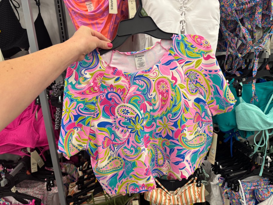 hand holding paisley swim crop top on hanger in store