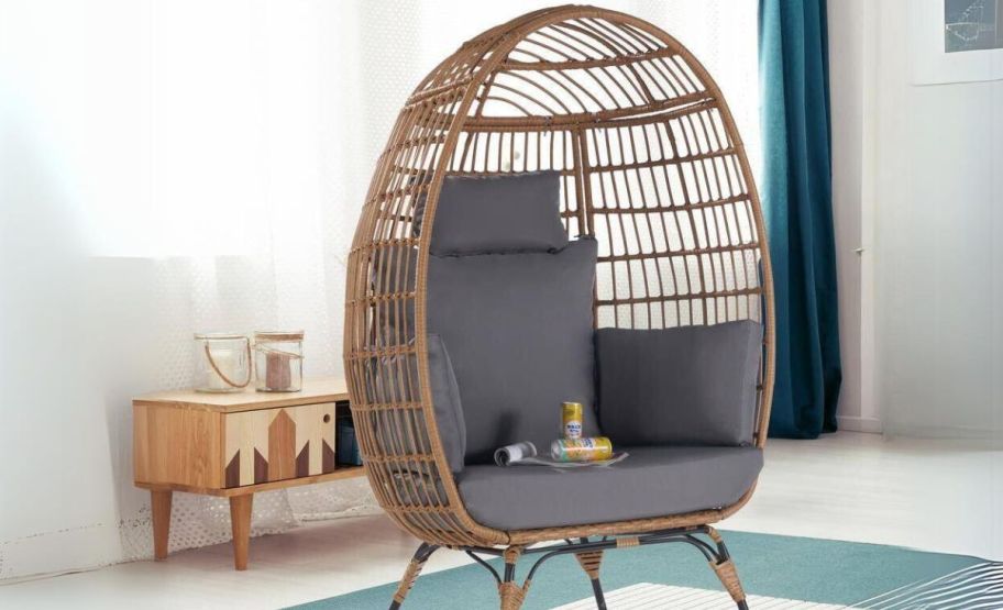 a brown wicker egg chair with gray cushions in a living room