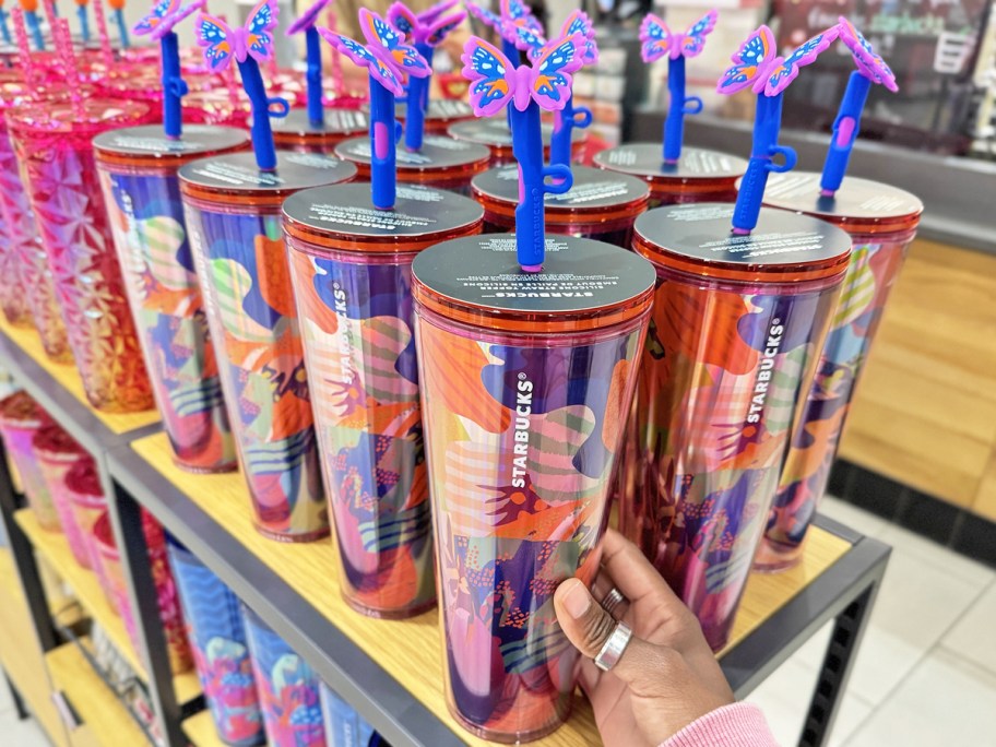 hand touching starbucks tumbler with a blue & purple butterfly straw topper