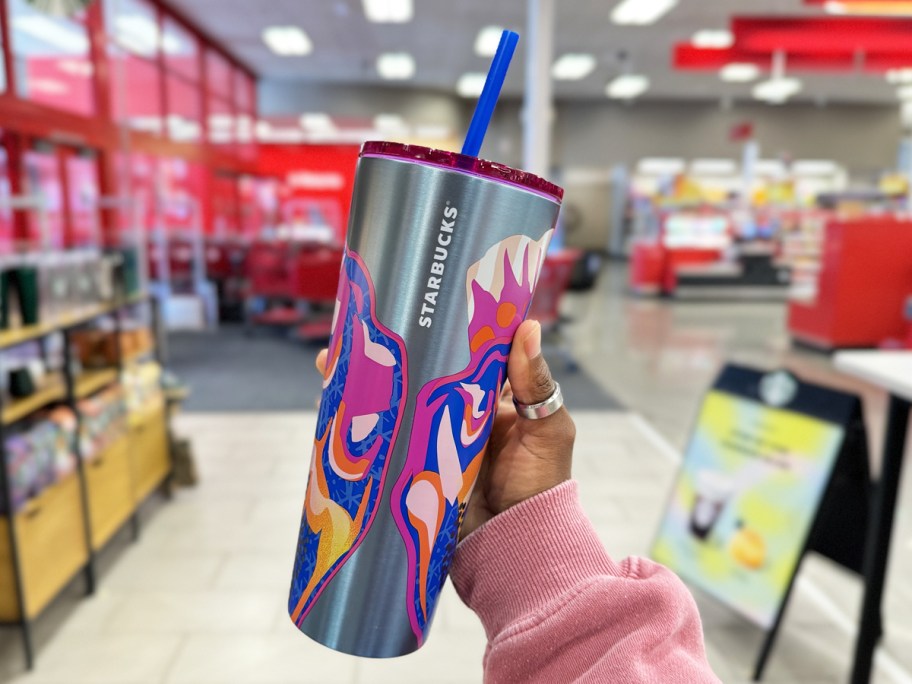 hand holding up a metal starbucks cold cup in store