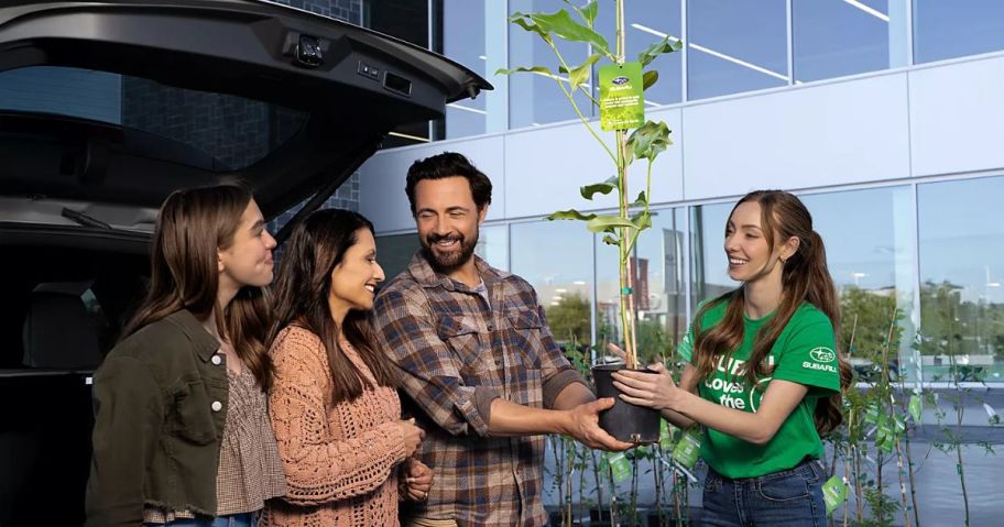 Subaru Employee handing a family a small tree in a pot