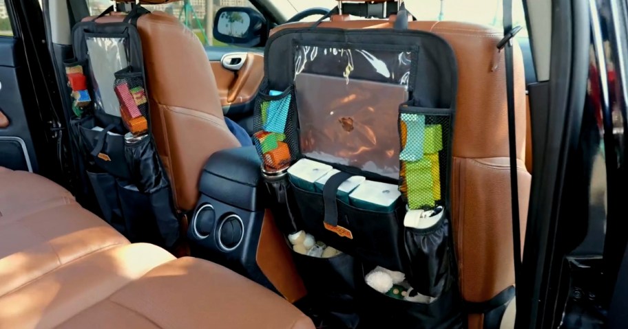 inside of a car with brown leather seats, showing black car seat organizers with a a variety of items in them