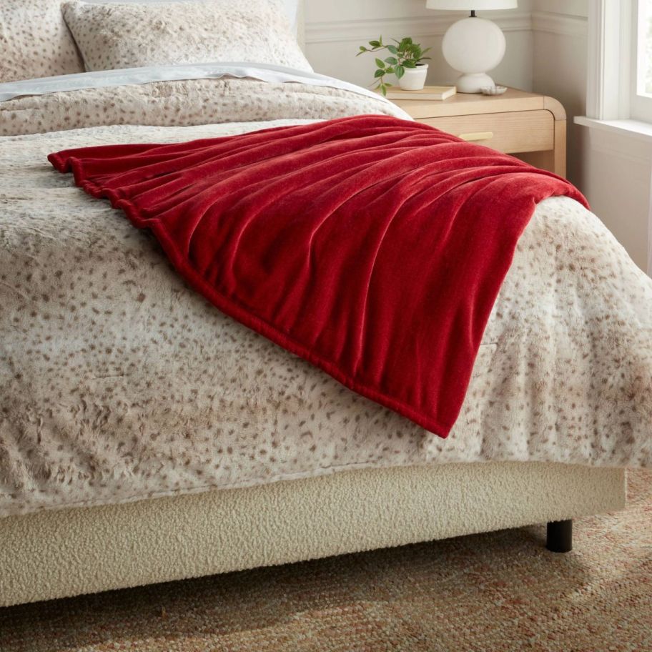 a red faux fur blanket draped across the foot of a bed