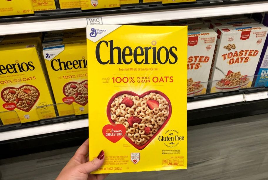 hand holding a box of Cheerios in a store