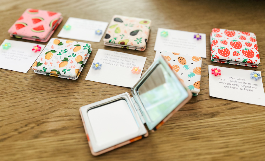 close up of compact mirror in front of notes to teachers and fruit covered mirrors