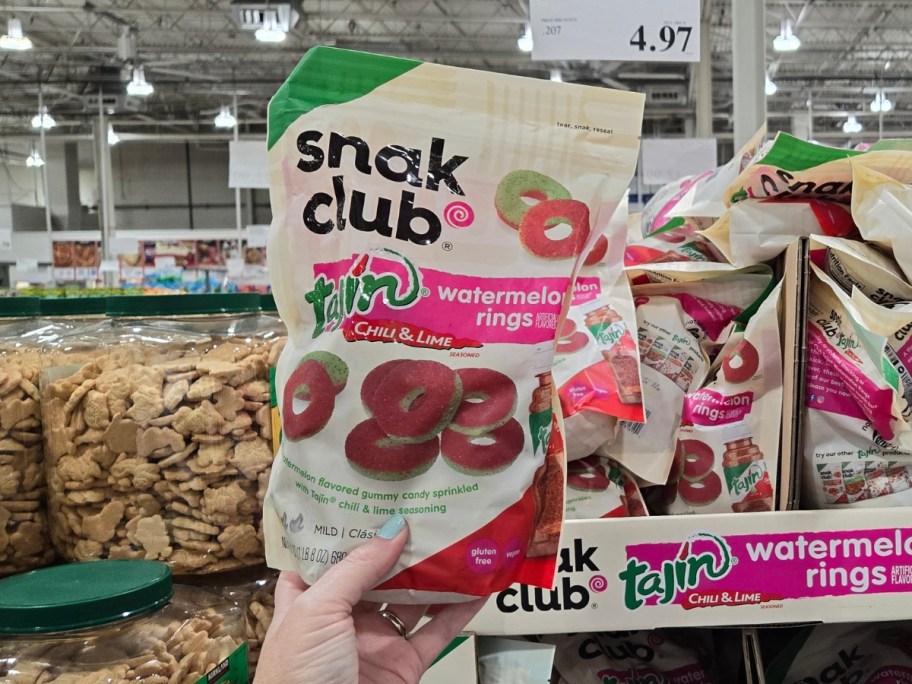 hand holding a bag of Snack Club Watermelon Rings candy - more packs behind it on display in Costco