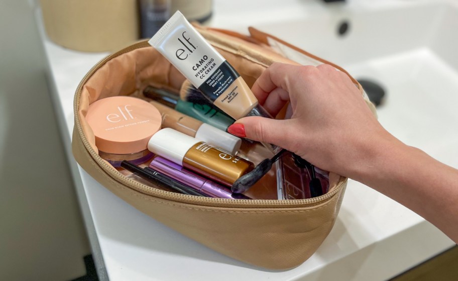 hand reaching into a makeup case for elf cosmetics products