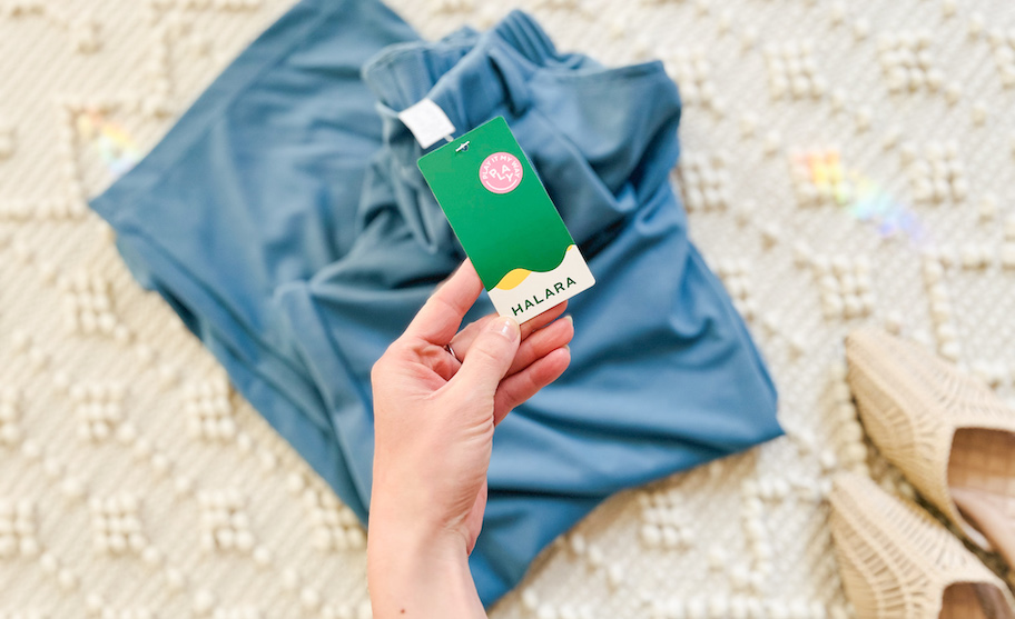 hand holding a halara tag on blue wide leg pants on tufted carpet