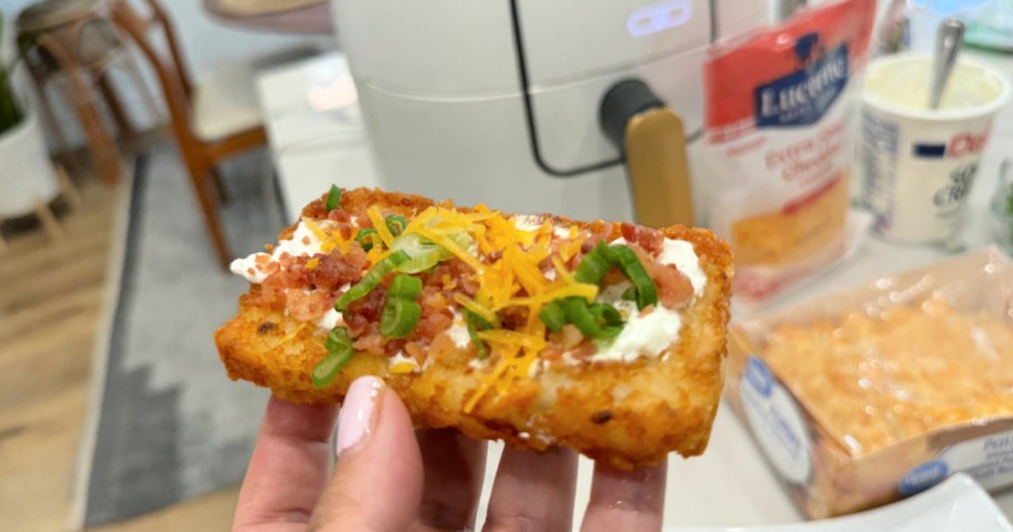 holding a loaded potato hasbrown with cheese and bacon