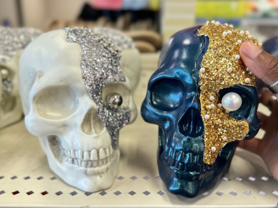 a woman's hand holding a ceramic jewel encrusted skull