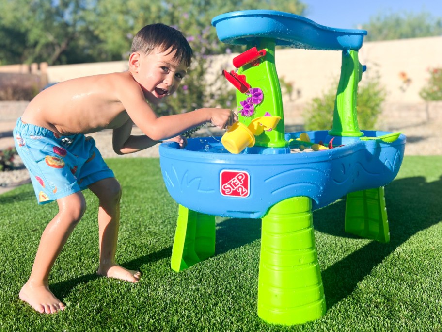 boy smiling standing at water table