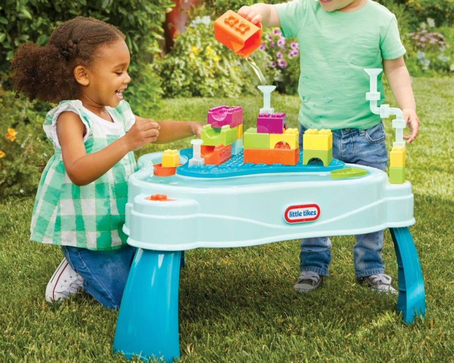 two kids near water table with building blocks on top