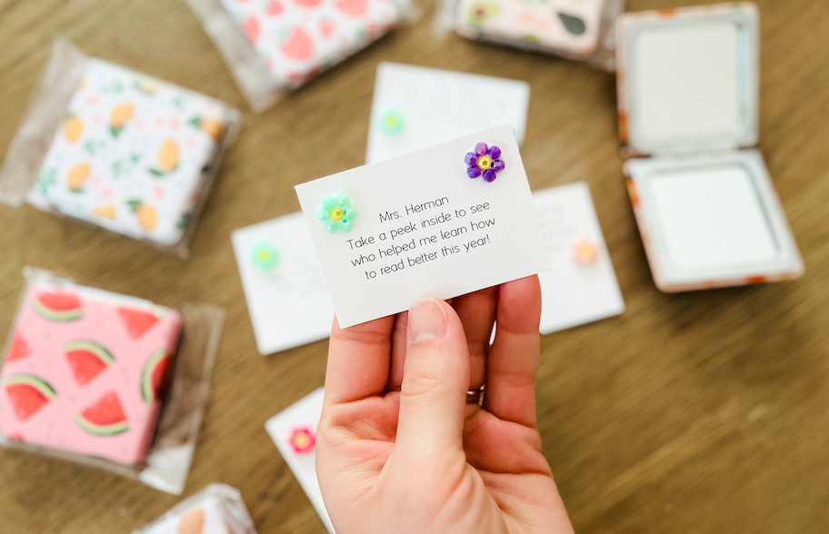 hand holding a note to a teacher with beaded flowers on corners