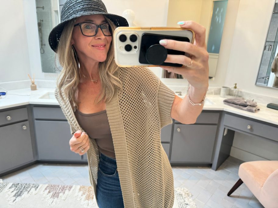woman in black hat and tan cardigan taking selfie