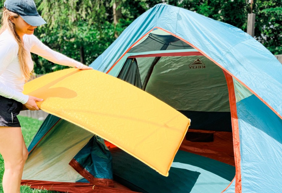 woman pulling out mattress from tent