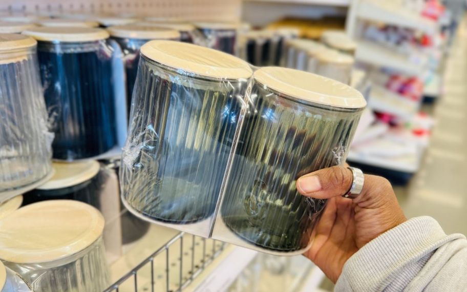 a womans hand holding a 2 pack of glass storage jars