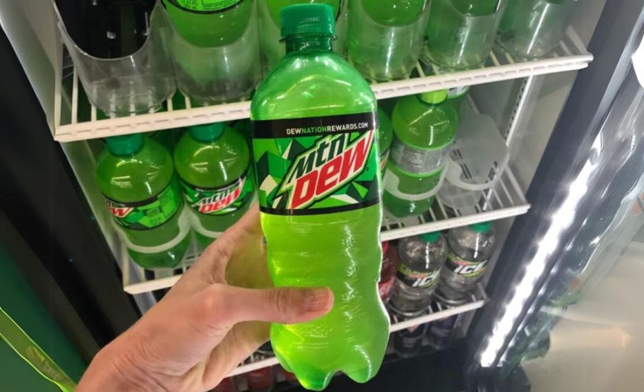 a mans hand holding a 20oz bottle of mountain dew