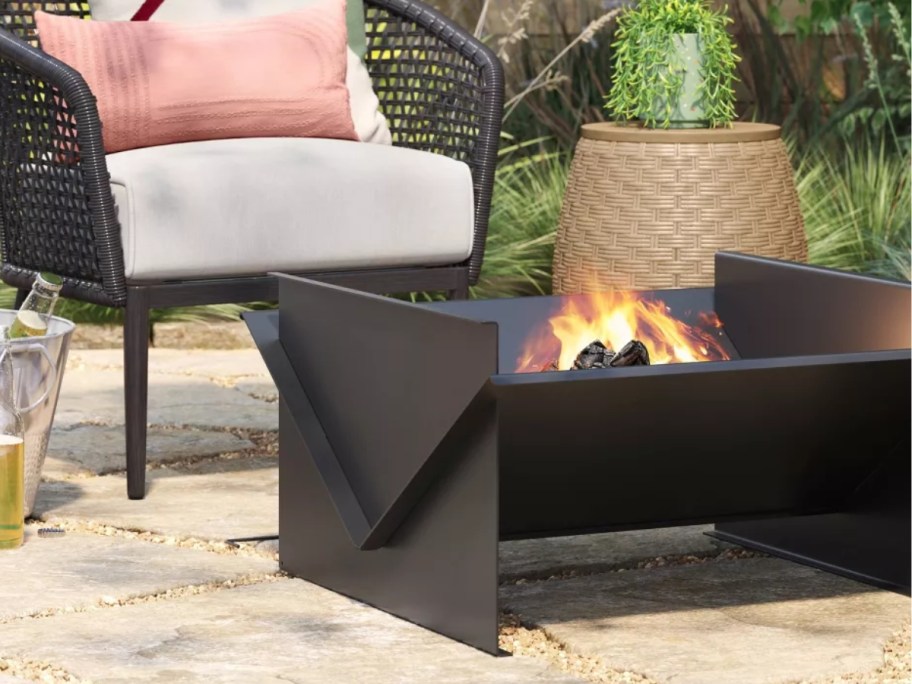 a black fire pit by a chair on a patio