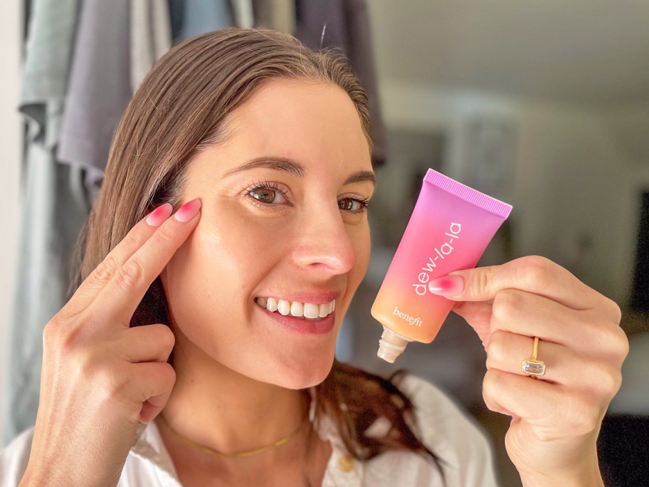 woman using fingers to apply benefit liquid highlighter to cheek