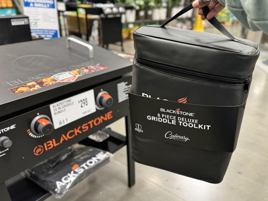 hand holding up a Blackstone griddle toolkit set next to Blackstone griddle