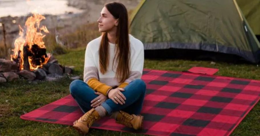 woman camping while sitting on a Columbia Packable Stadium Blanket