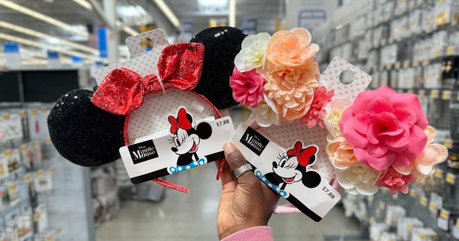 A person holding 2 pairs of Minnie Mouse Ears headbands