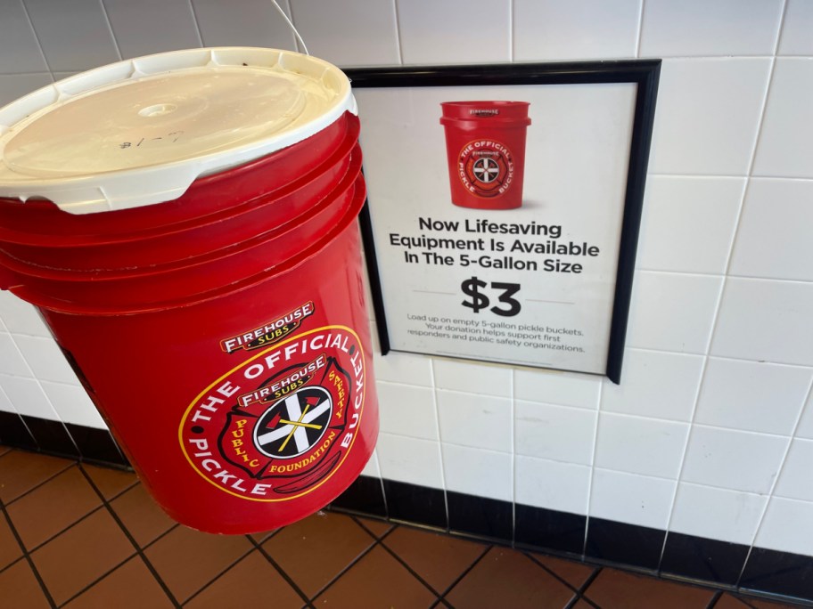 A firehouse subs pickle. bucket next to a fundraising sign for first responders