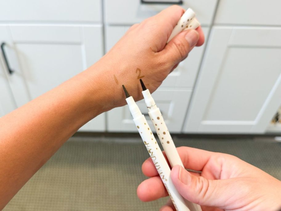 A woman holding 2 pens 