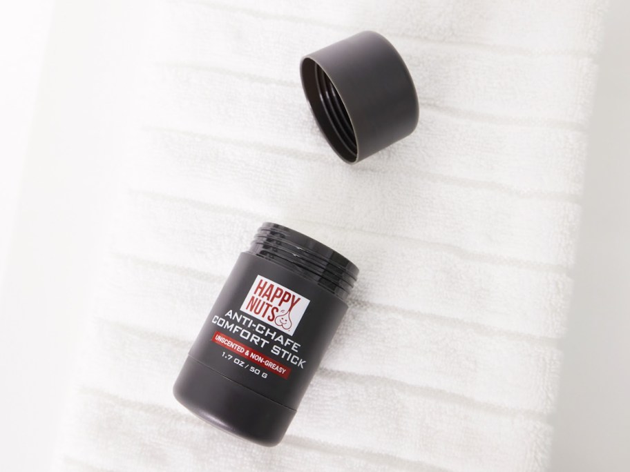 Happy Nuts Anti-Chafe Comfort Stick laying on a towel with it's lid off