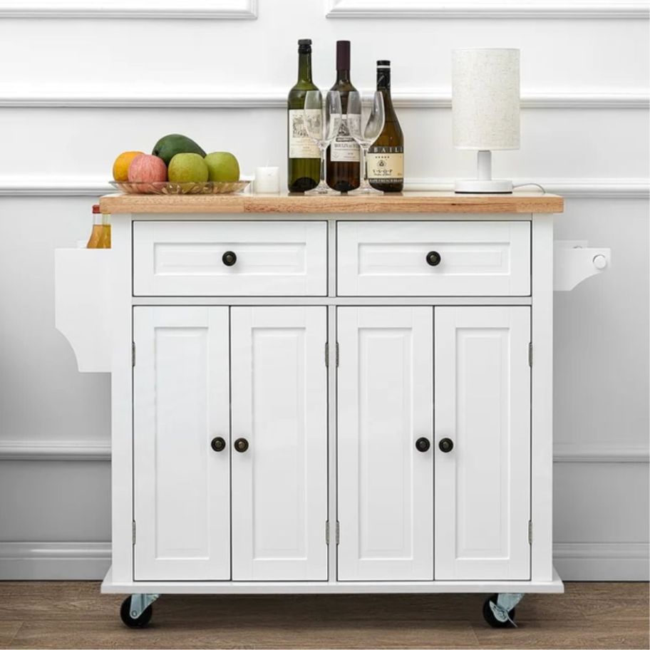 a white rolling kitchen cart shown with bar items 