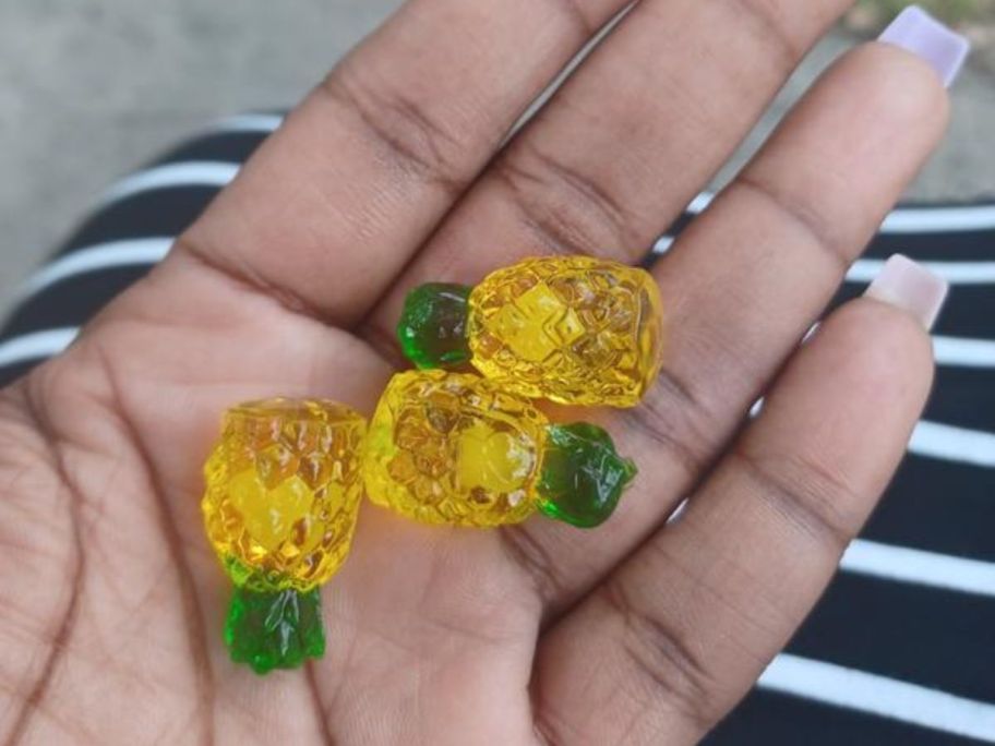 A hand holding 3 Pineapple Burst Gummies