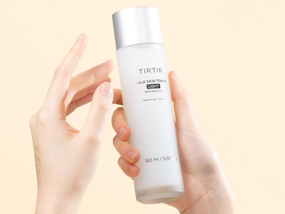 hand holding white bottle of TIRTIR Milk Skin Toner