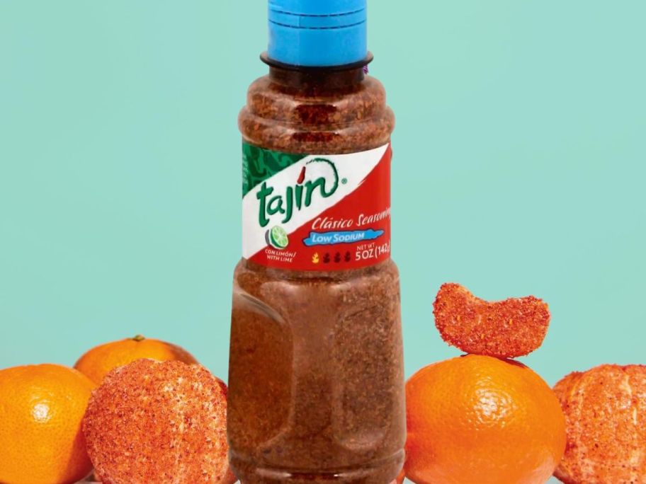 Tajín Clásico Reduced Sodium Seasoning 5 oz sitting in between mandarin oranges