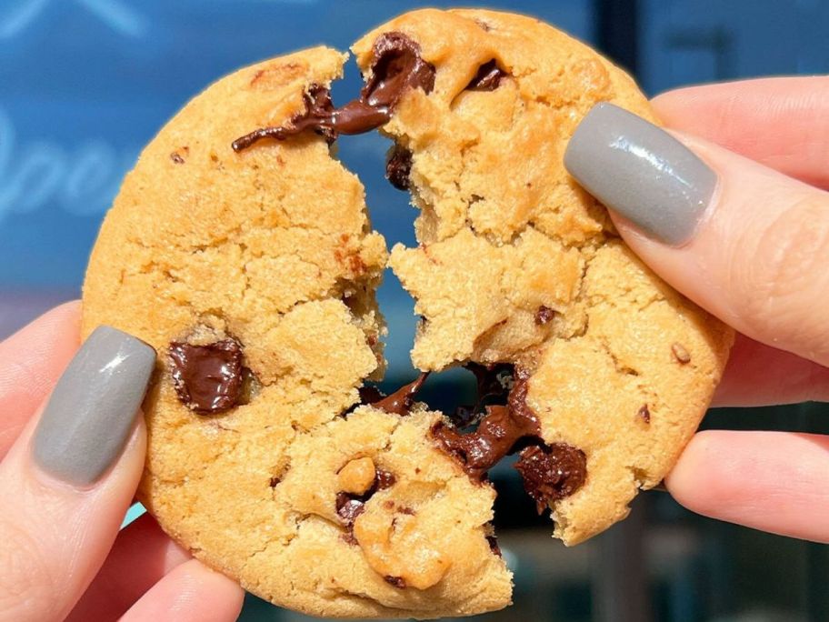 Hand breaking apart a Tiff's Treats Chocolate Chip Cookie