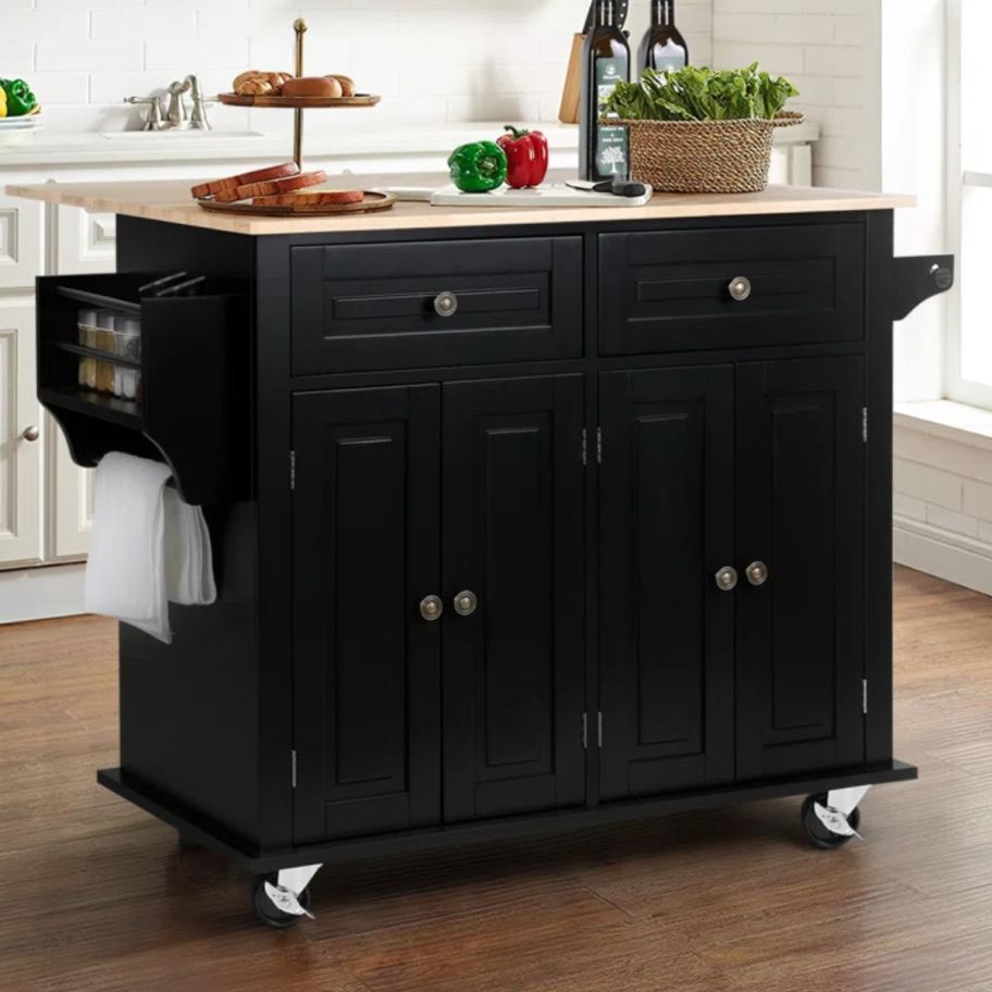 a black wooden rolling kitchen cart shown with food items 