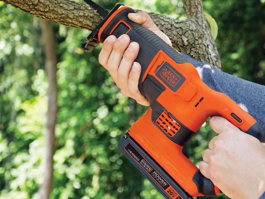 hand using reciprocating saw on tree branch