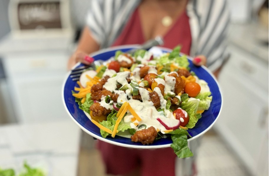 holding a salad with wingers sticky chicken fingers