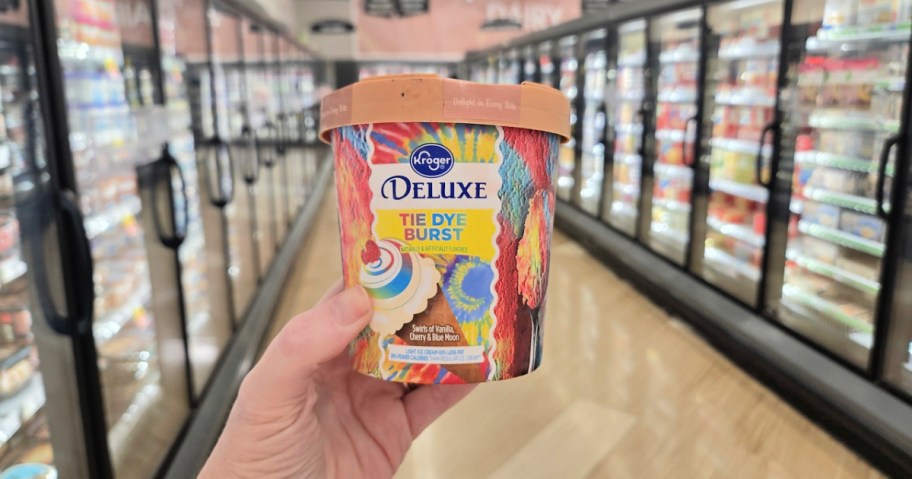 woman holding up a pint of kroger ice cream in a store aisle