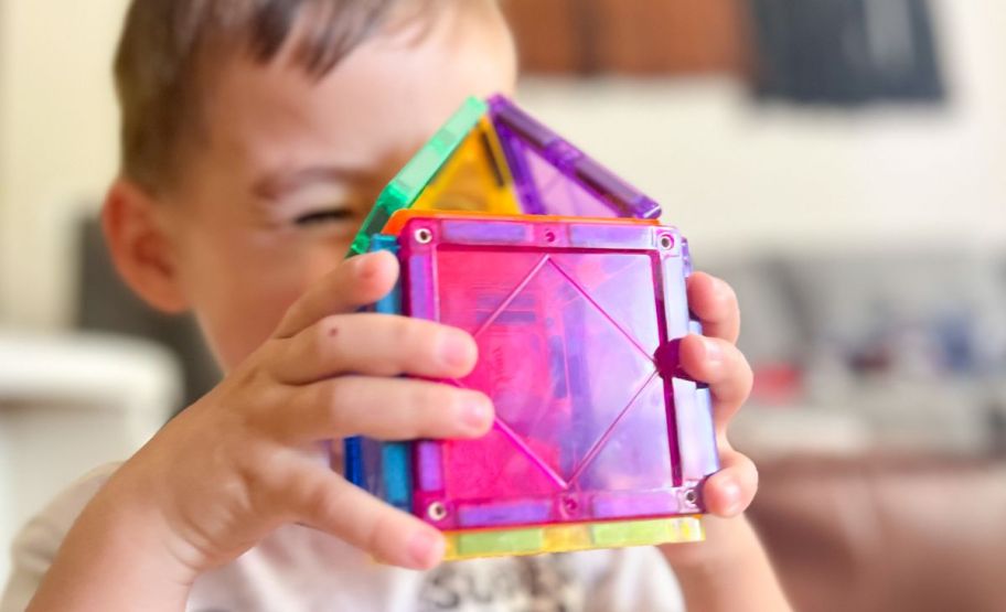 a little boy playing with a magnetic tile set